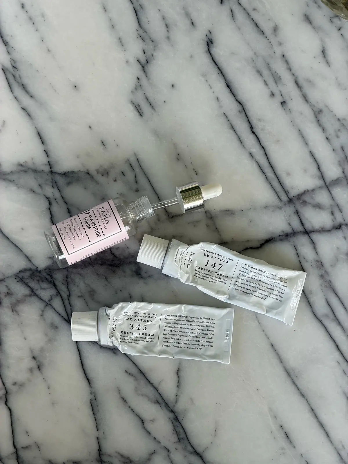 Empty beauty product containers arranged on a marble surface.