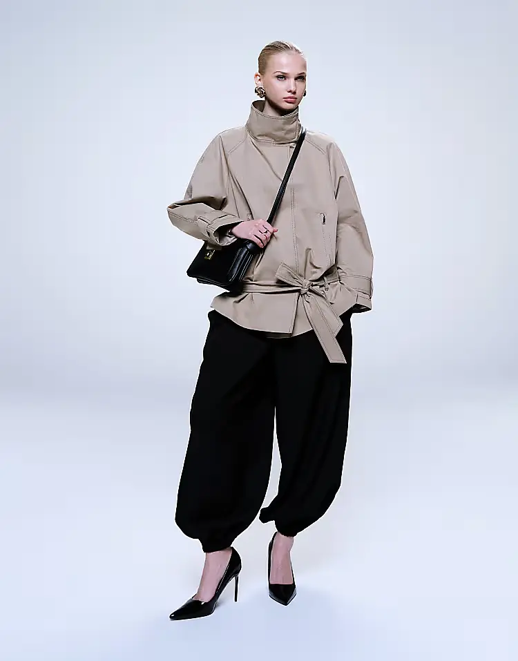 Model wearing a stone ASOS DESIGN trench coat with a belt.