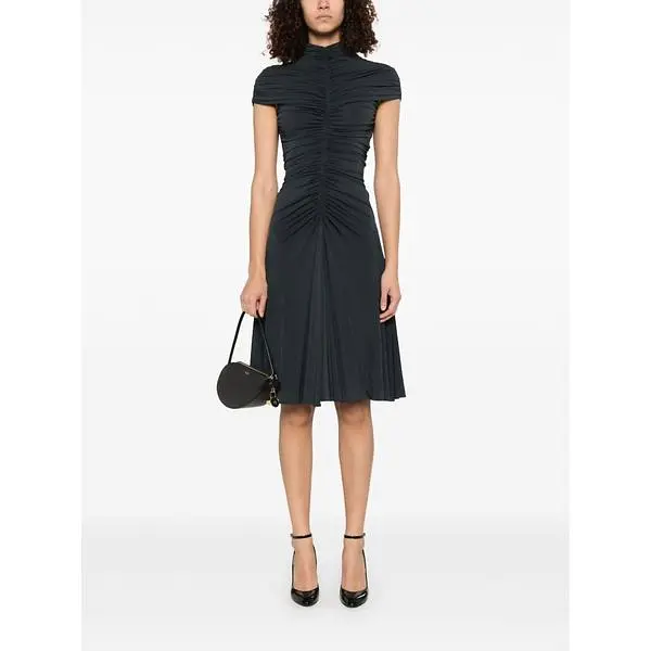 Model wearing an Alaïa dark short-sleeved midi dress with a gathered waist.