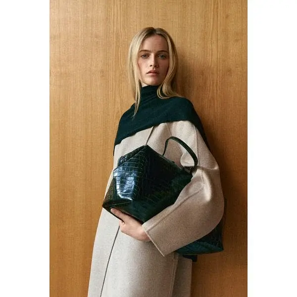 Modella con una borsa bowling scura effetto coccodrillo.